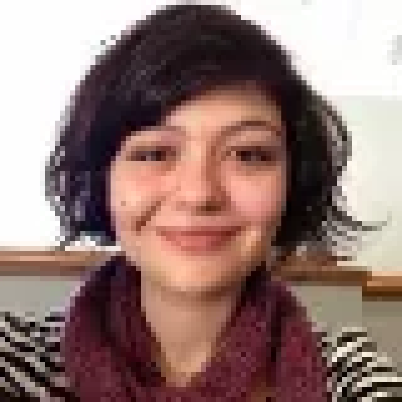 Alicia Silvestri, smiling, wearing professional attire, with a neutral background