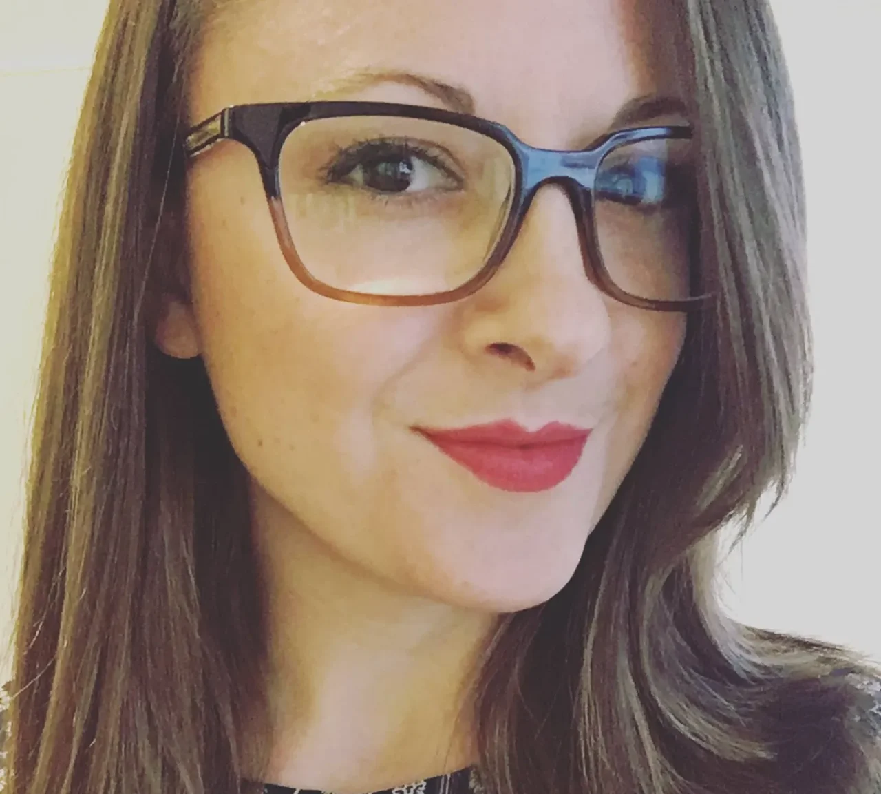 Jenna Scatena, smiling, wearing professional attire, with a neutral background