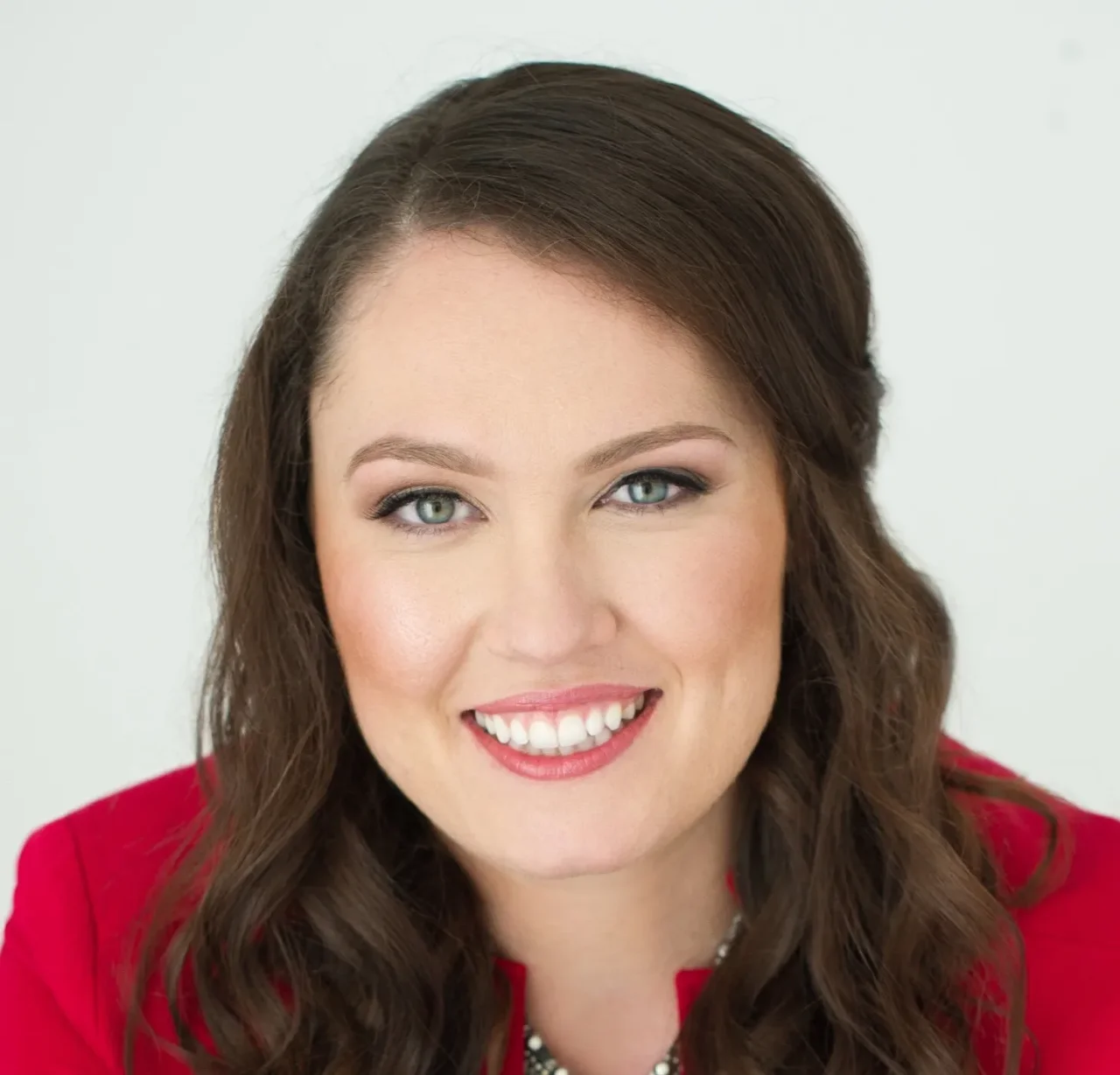 Laura Briggs, smiling, wearing professional attire, with a neutral background